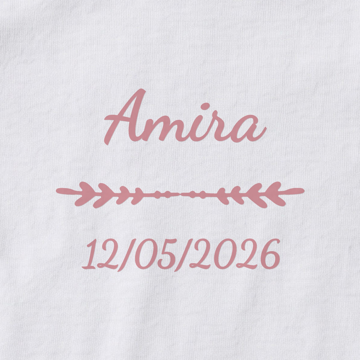 Body bébé personnalisé Amira — gros plan du marquage « Amira », ornement Flèche et date de naissance « 12/05/2026 »