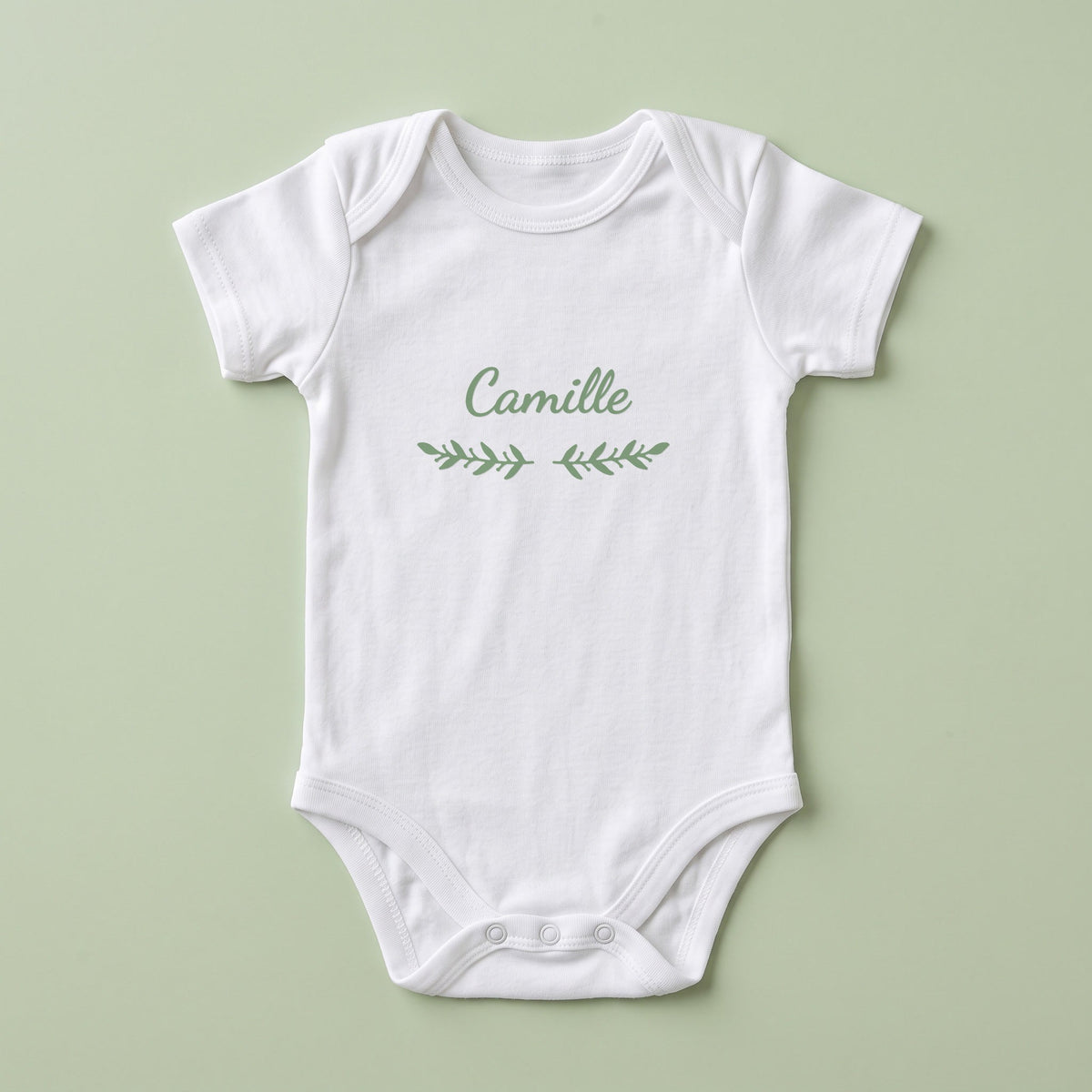 Body bébé blanc personnalisé Camille — prénom « Camille » marqué sur la poitrine, ornement Rameaux