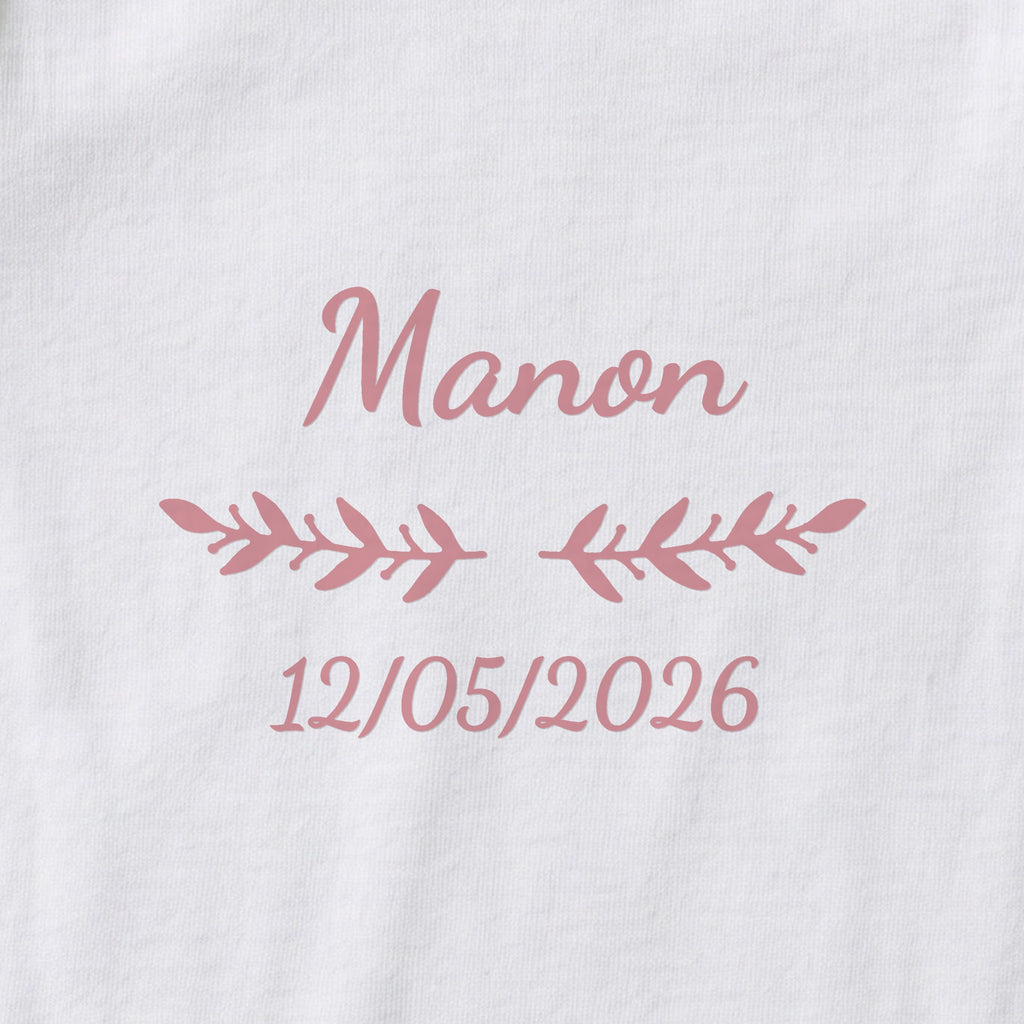 Body bébé personnalisé Manon — gros plan du marquage « Manon », ornement Rameaux et date de naissance « 12/05/2026 »