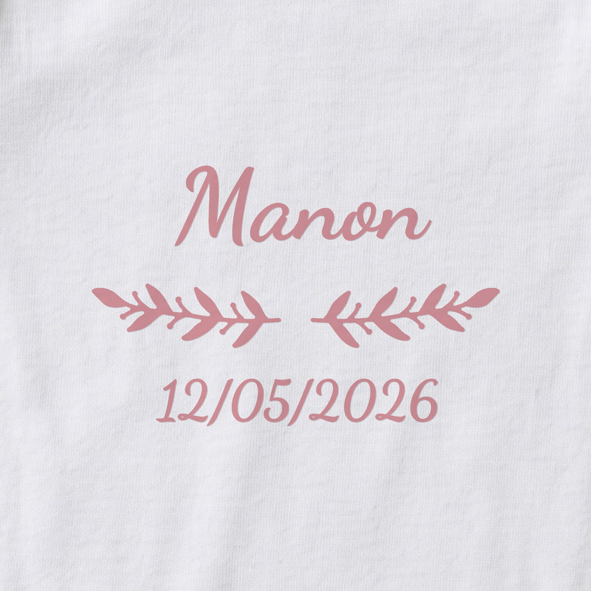 Body bébé personnalisé Manon — gros plan du marquage « Manon », ornement Rameaux et date de naissance « 12/05/2026 »