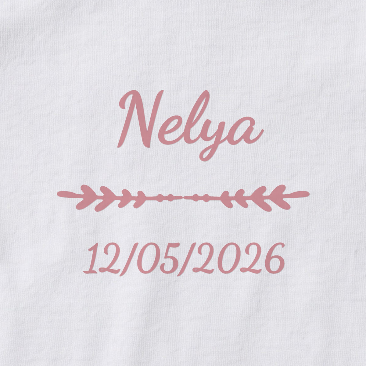 Body bébé personnalisé Nelya — gros plan du marquage « Nelya », ornement Flèche et date de naissance « 12/05/2026 »