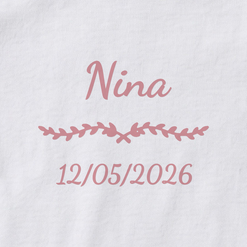 Body bébé personnalisé Nina — gros plan du marquage « Nina », ornement Liane et date de naissance « 12/05/2026 »