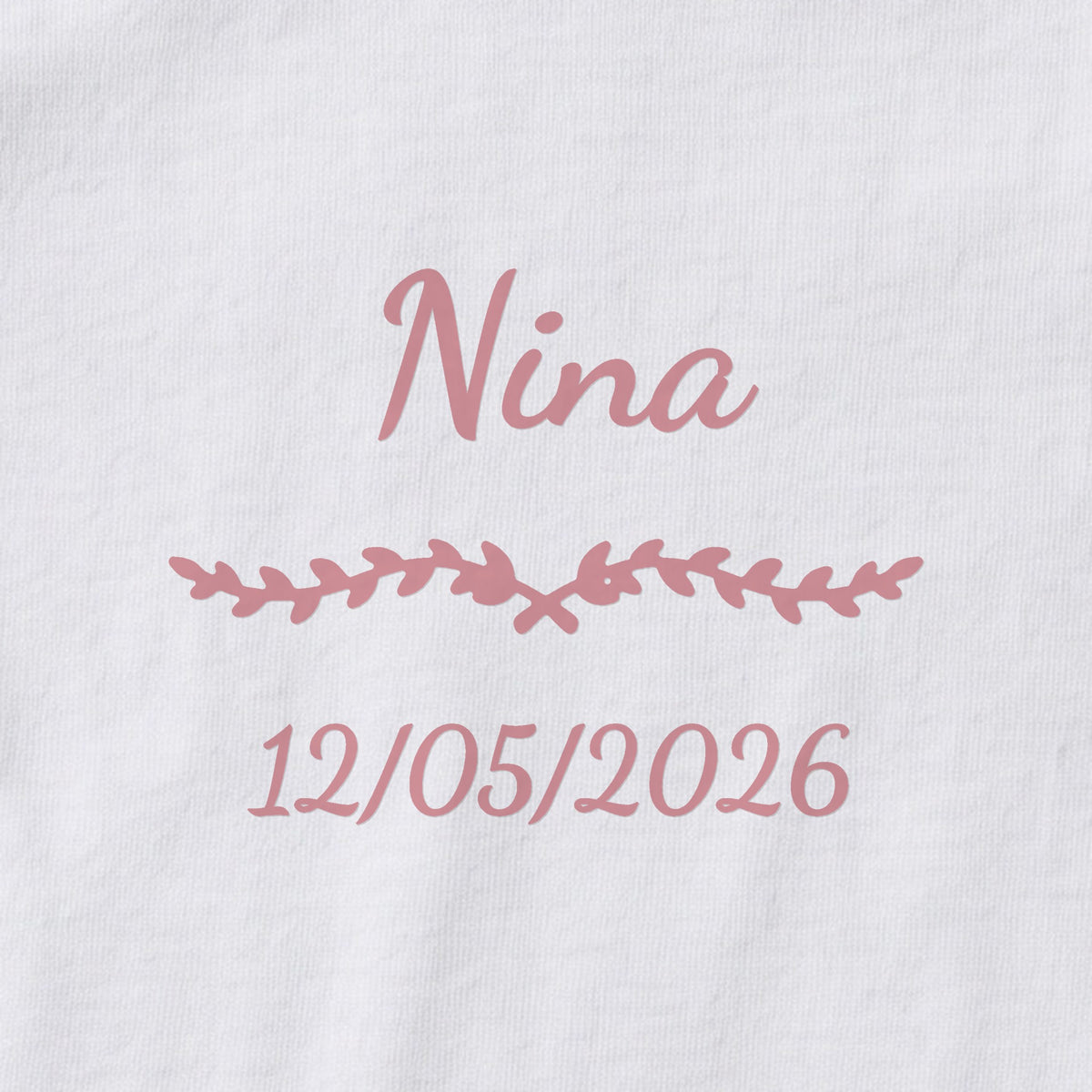 Body bébé personnalisé Nina — gros plan du marquage « Nina », ornement Liane et date de naissance « 12/05/2026 »