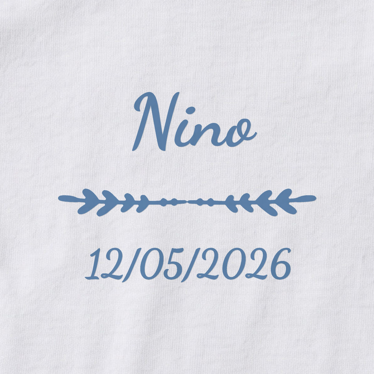 Body bébé personnalisé Nino — gros plan du marquage « Nino », ornement Flèche et date de naissance « 12/05/2026 »