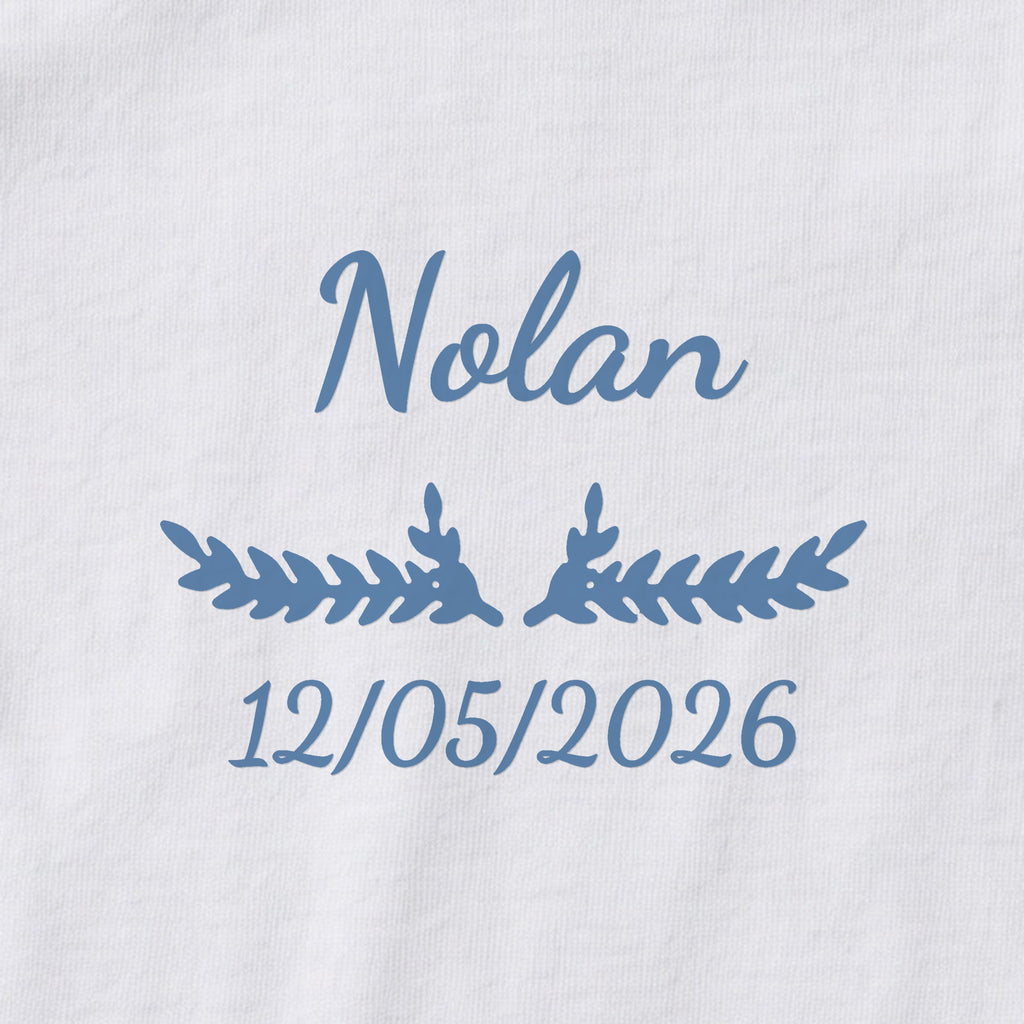Body bébé personnalisé Nolan — gros plan du marquage « Nolan », ornement Bouquet et date de naissance « 12/05/2026 »