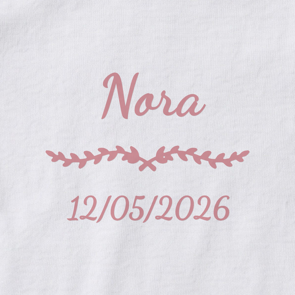 Body bébé personnalisé Nora — gros plan du marquage « Nora », ornement Liane et date de naissance « 12/05/2026 »