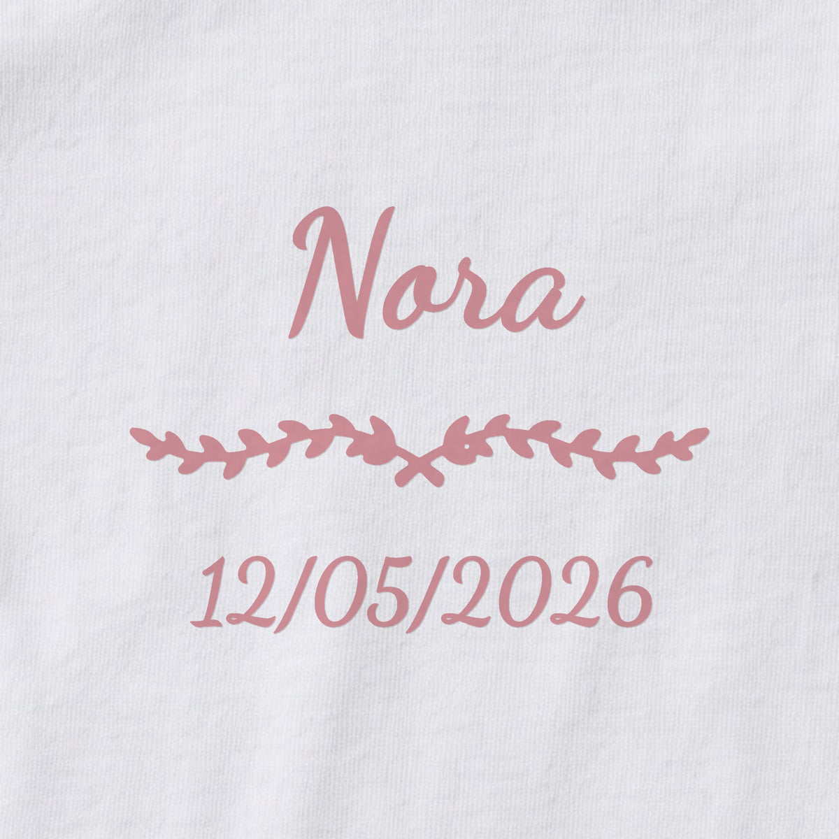 Body bébé personnalisé Nora — gros plan du marquage « Nora », ornement Liane et date de naissance « 12/05/2026 »
