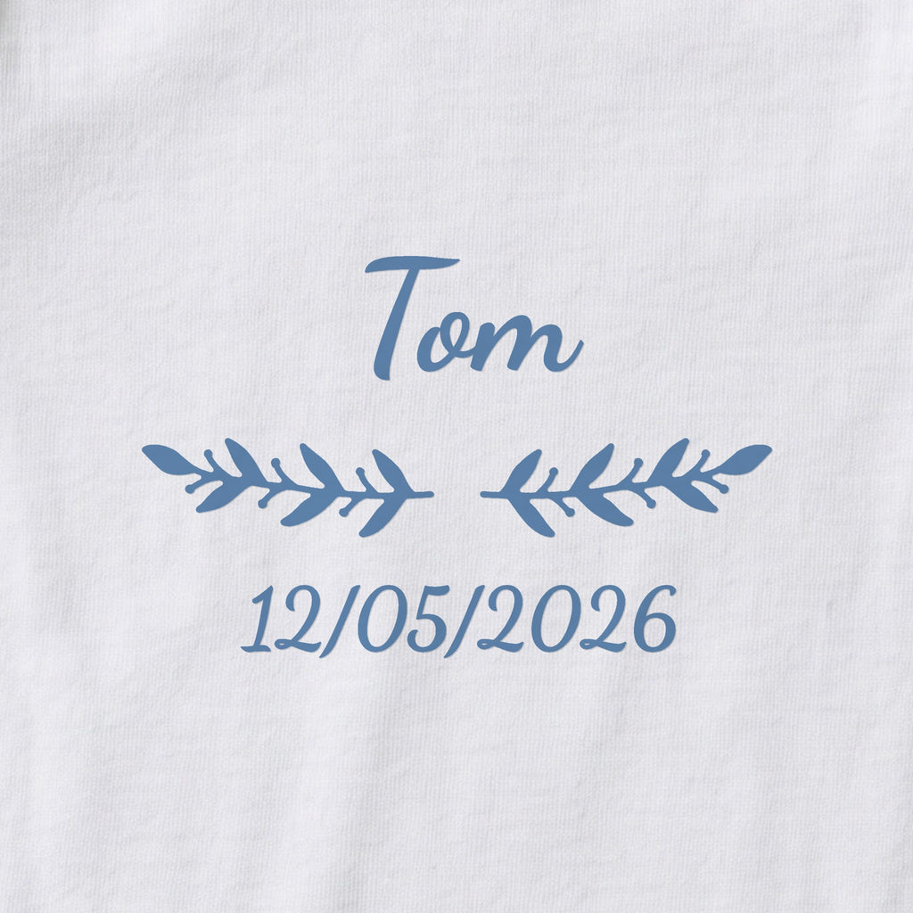 Body bébé personnalisé Tom — gros plan du marquage « Tom », ornement Rameaux et date de naissance « 12/05/2026 »