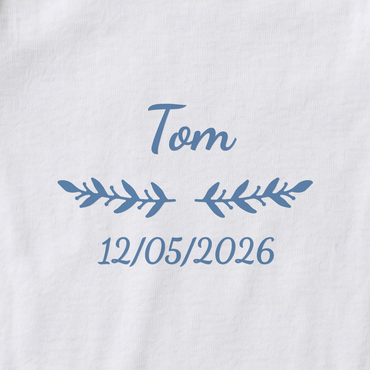 Body bébé personnalisé Tom — gros plan du marquage « Tom », ornement Rameaux et date de naissance « 12/05/2026 »
