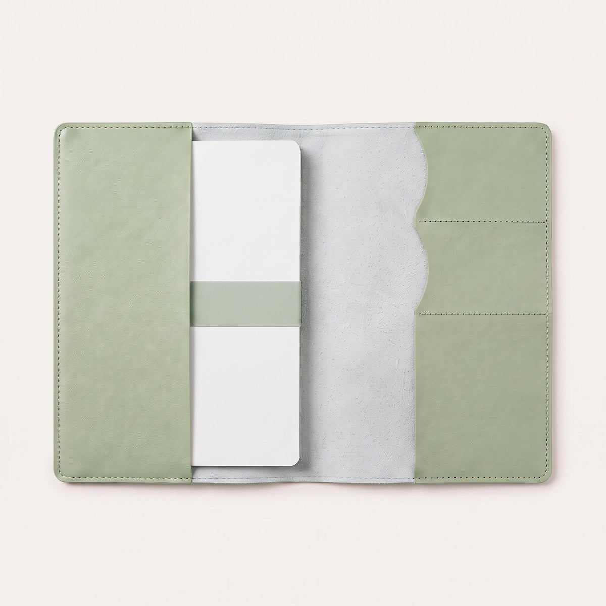Protège carnet de santé personnalisé — ouvert avec un carnet glissé sous le rabat gauche (visuel de mise en scène, coloris Vert sauge)