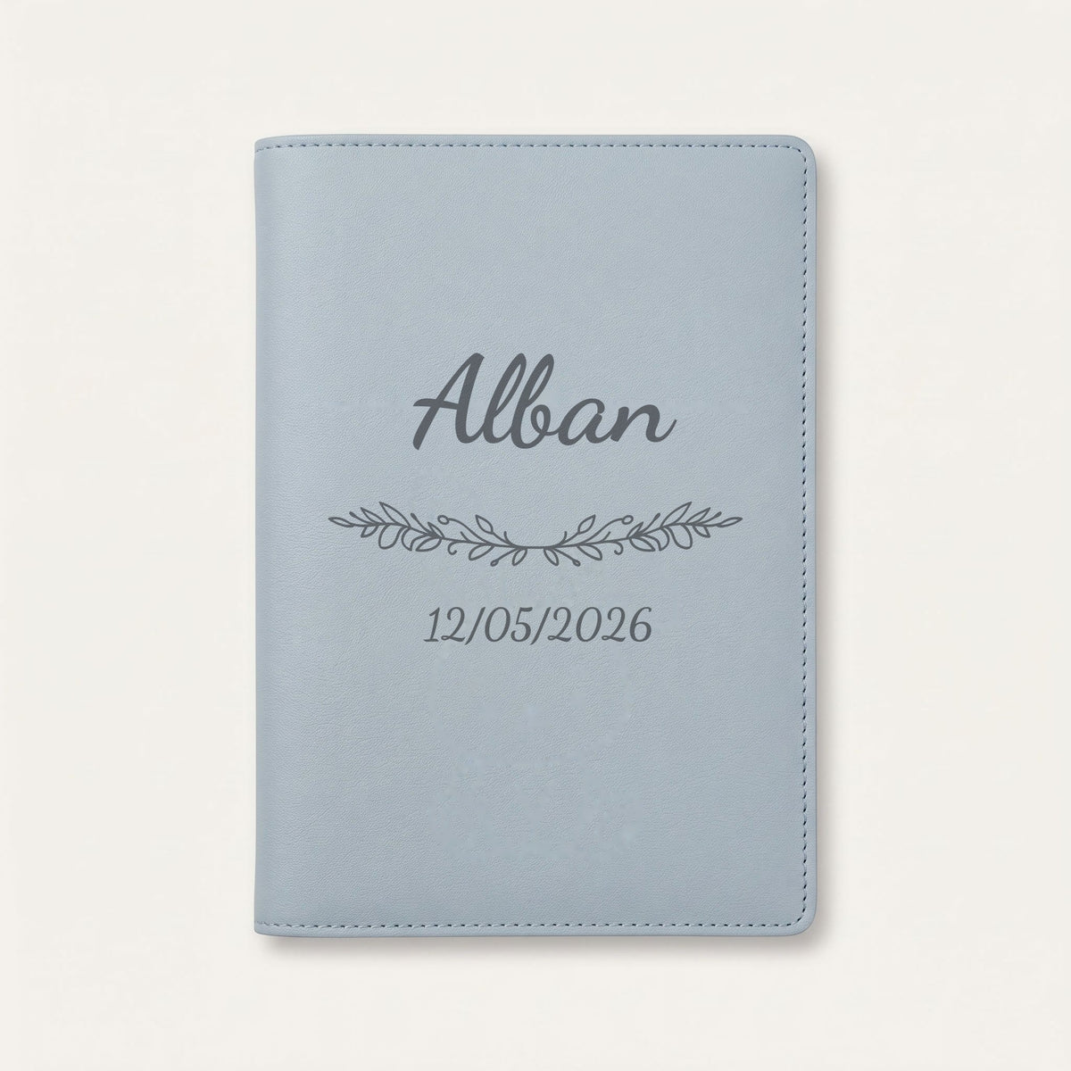 Protège carnet de santé personnalisé Alban — Bleu nuage — prénom « Alban », ornement Guirlande et date de naissance « 12/05/2026 » gravés