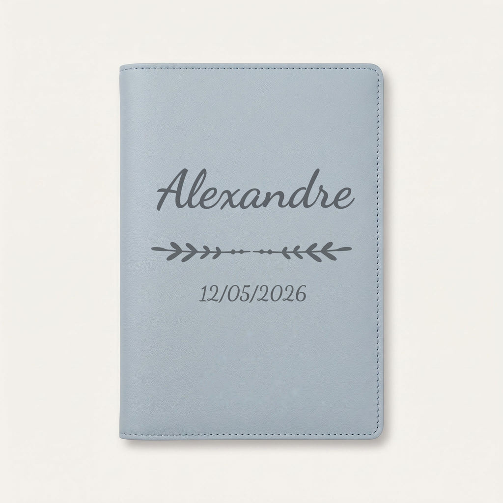 Protège carnet de santé personnalisé Alexandre — Bleu nuage — prénom « Alexandre », ornement Flèche et date de naissance « 12/05/2026 » gravés