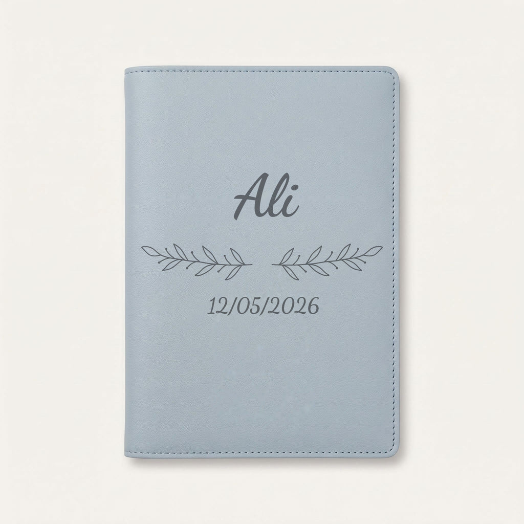 Protège carnet de santé personnalisé Ali — Bleu nuage — prénom « Ali », ornement Rameaux et date de naissance « 12/05/2026 » gravés