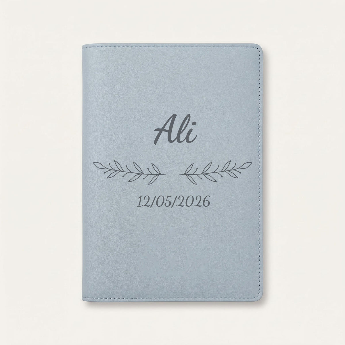 Protège carnet de santé personnalisé Ali — Bleu nuage — prénom « Ali », ornement Rameaux et date de naissance « 12/05/2026 » gravés