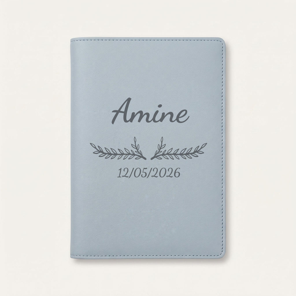 Protège carnet de santé personnalisé Amine — Bleu nuage — prénom « Amine », ornement Bouquet et date de naissance « 12/05/2026 » gravés