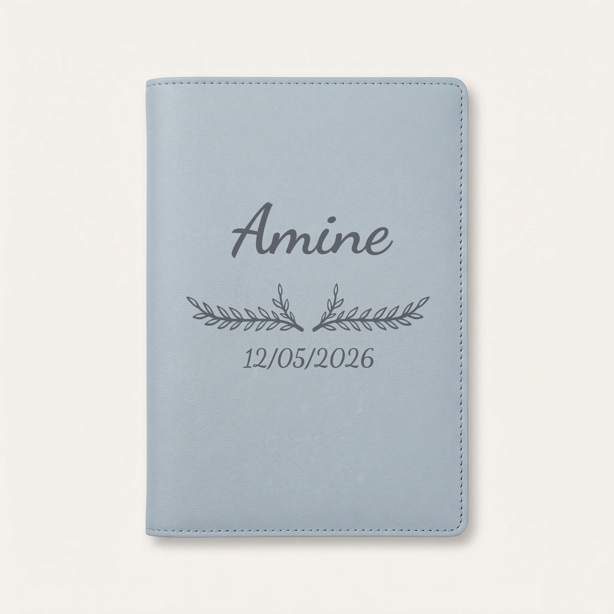 Protège carnet de santé personnalisé Amine — Bleu nuage — prénom « Amine », ornement Bouquet et date de naissance « 12/05/2026 » gravés
