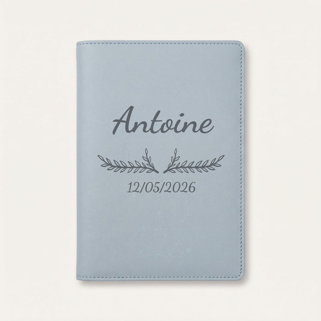 Protège carnet de santé personnalisé Antoine — Bleu nuage — prénom « Antoine », ornement Bouquet et date de naissance « 12/05/2026 » gravés