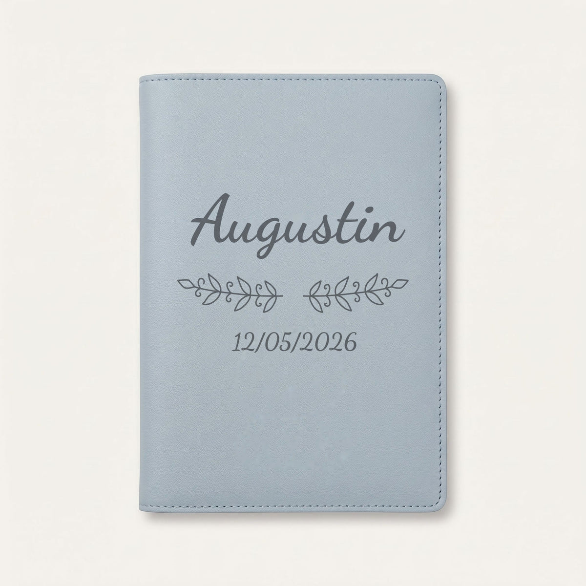 Protège carnet de santé personnalisé Augustin — Bleu nuage — prénom « Augustin », ornement Volutes et date de naissance « 12/05/2026 » gravés