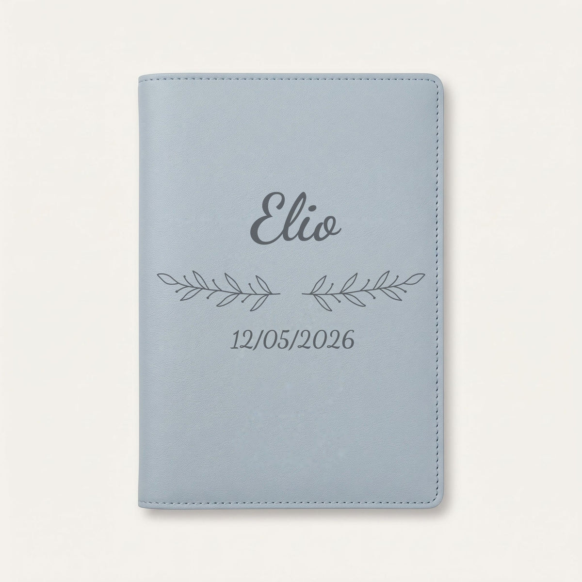 Protège carnet de santé personnalisé Elio — Bleu nuage — prénom « Elio », ornement Rameaux et date de naissance « 12/05/2026 » gravés