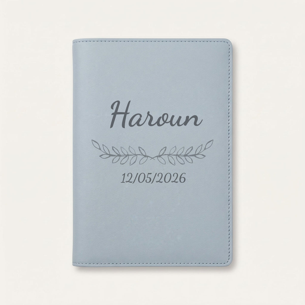 Protège carnet de santé personnalisé Haroun — Bleu nuage — prénom « Haroun », ornement Feuillage et date de naissance « 12/05/2026 » gravés