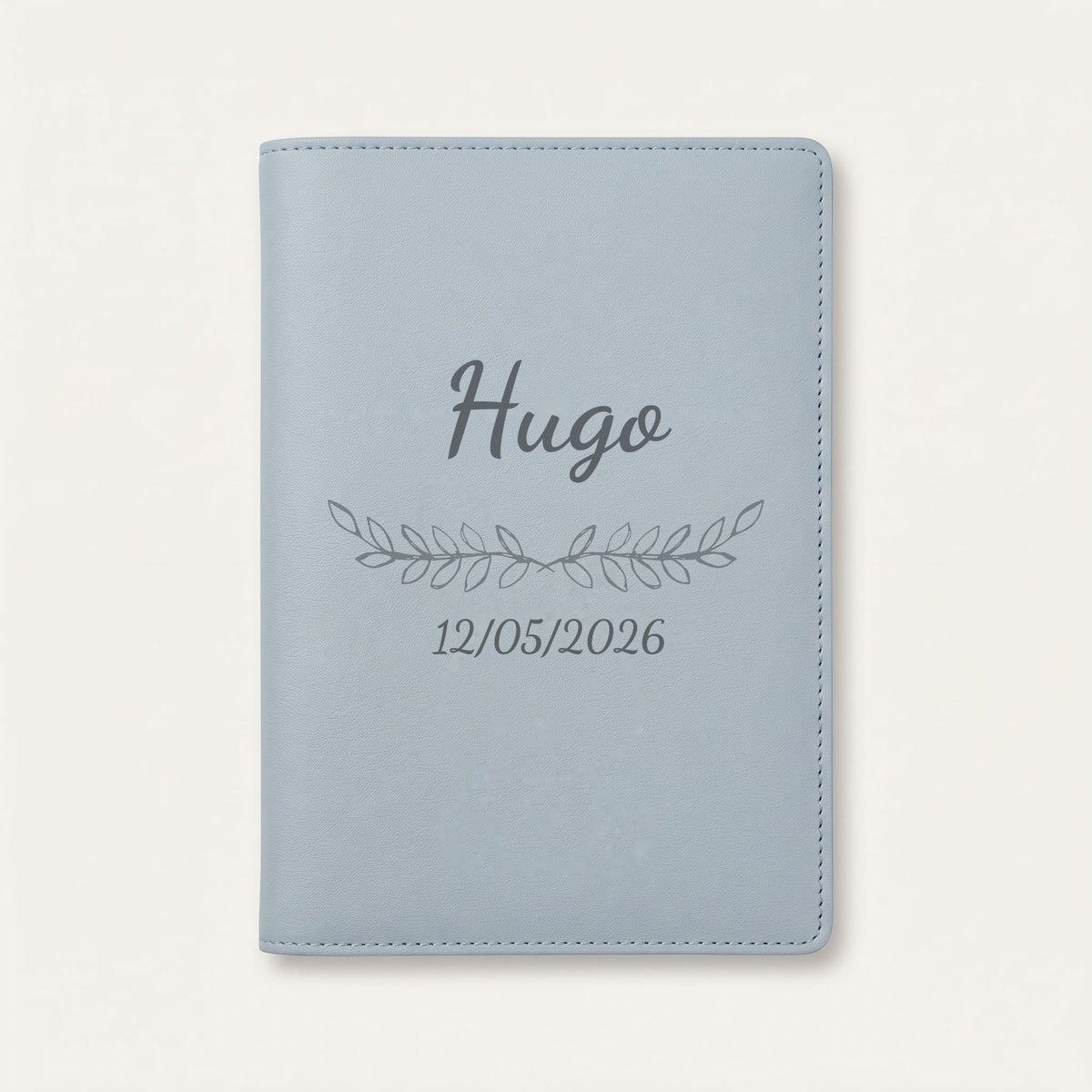Protège carnet de santé personnalisé Hugo — Bleu nuage — prénom « Hugo », ornement Feuillage et date de naissance « 12/05/2026 » gravés