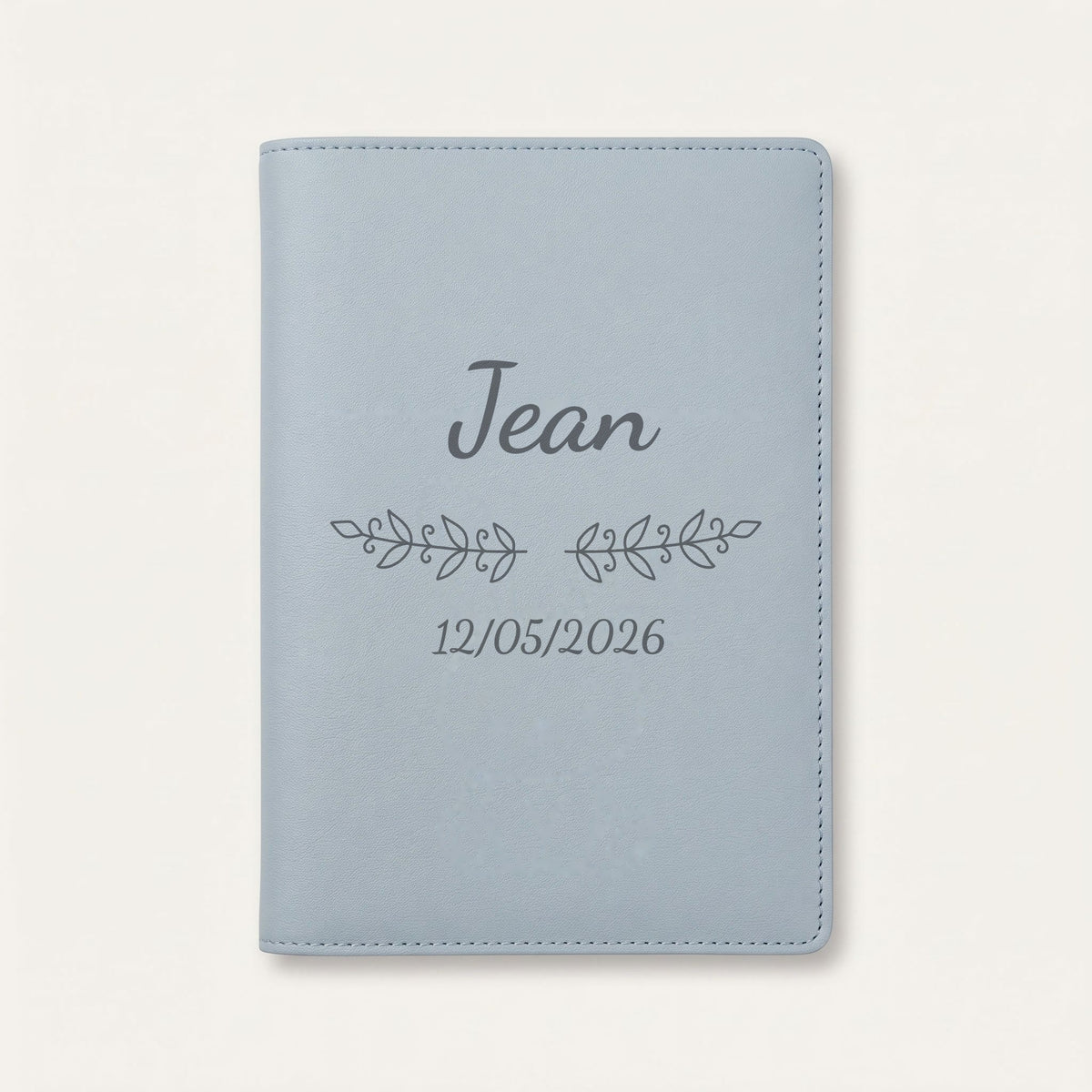 Protège carnet de santé personnalisé Jean — Bleu nuage — prénom « Jean », ornement Volutes et date de naissance « 12/05/2026 » gravés