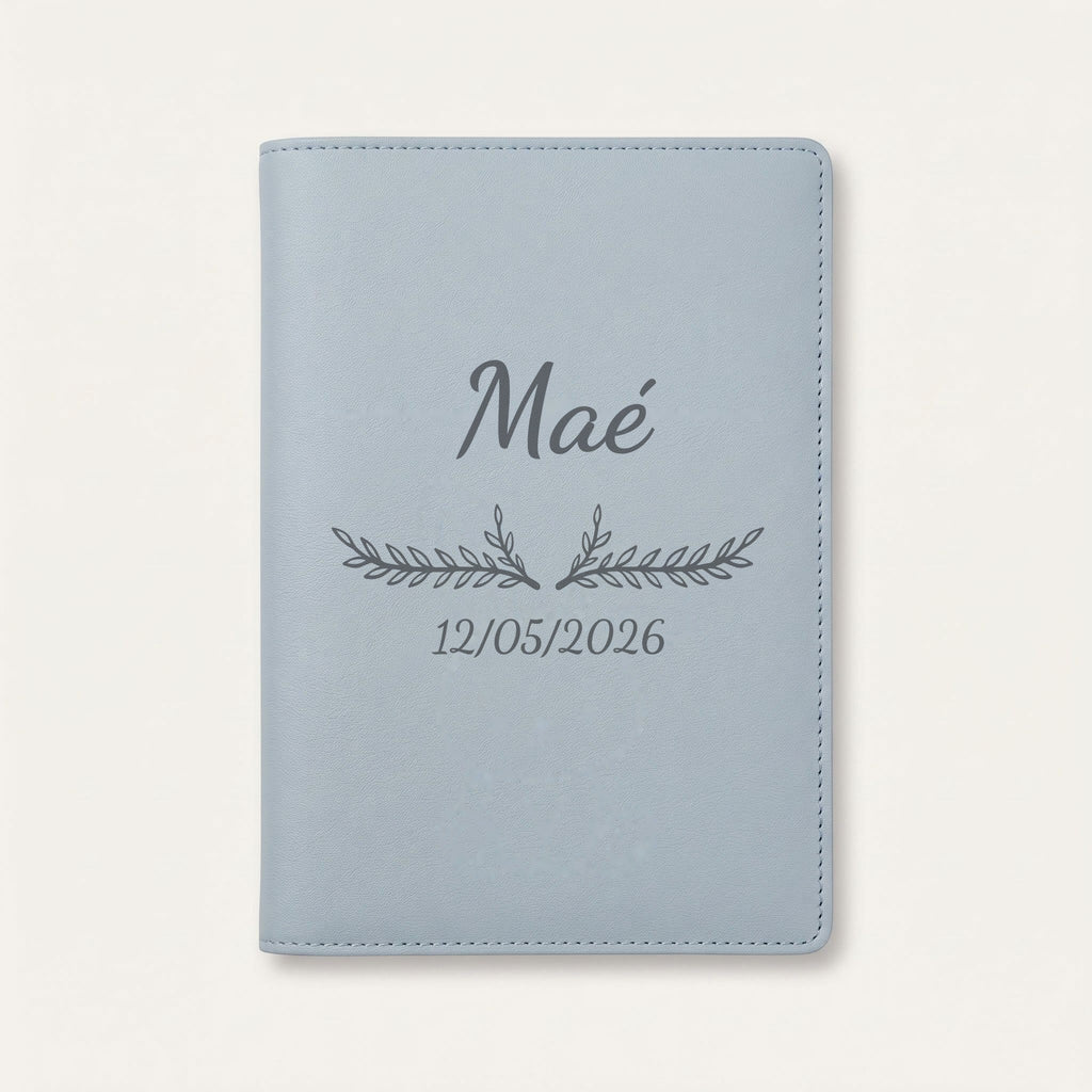 Protège carnet de santé personnalisé Maé — Bleu nuage — prénom « Maé », ornement Bouquet et date de naissance « 12/05/2026 » gravés