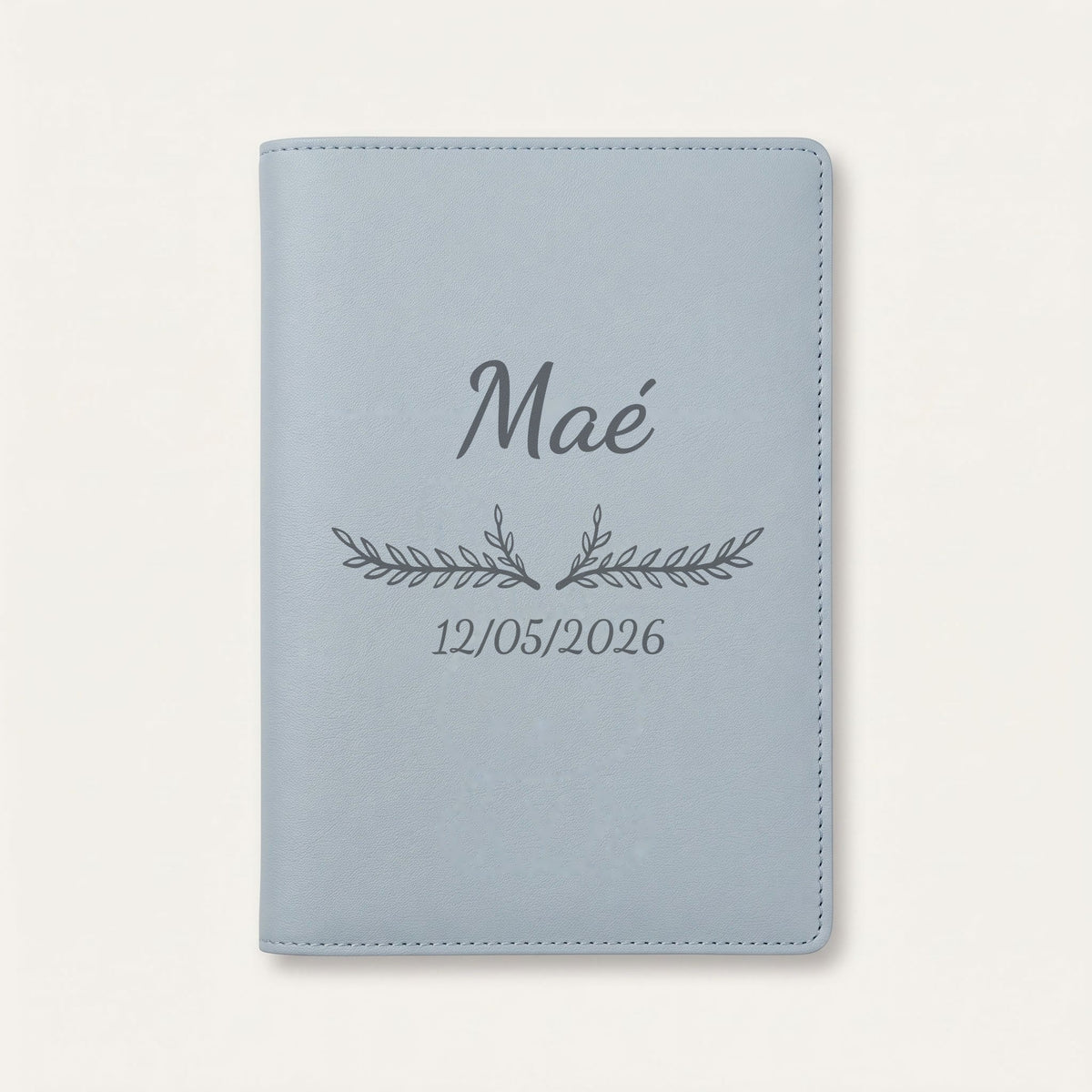 Protège carnet de santé personnalisé Maé — Bleu nuage — prénom « Maé », ornement Bouquet et date de naissance « 12/05/2026 » gravés