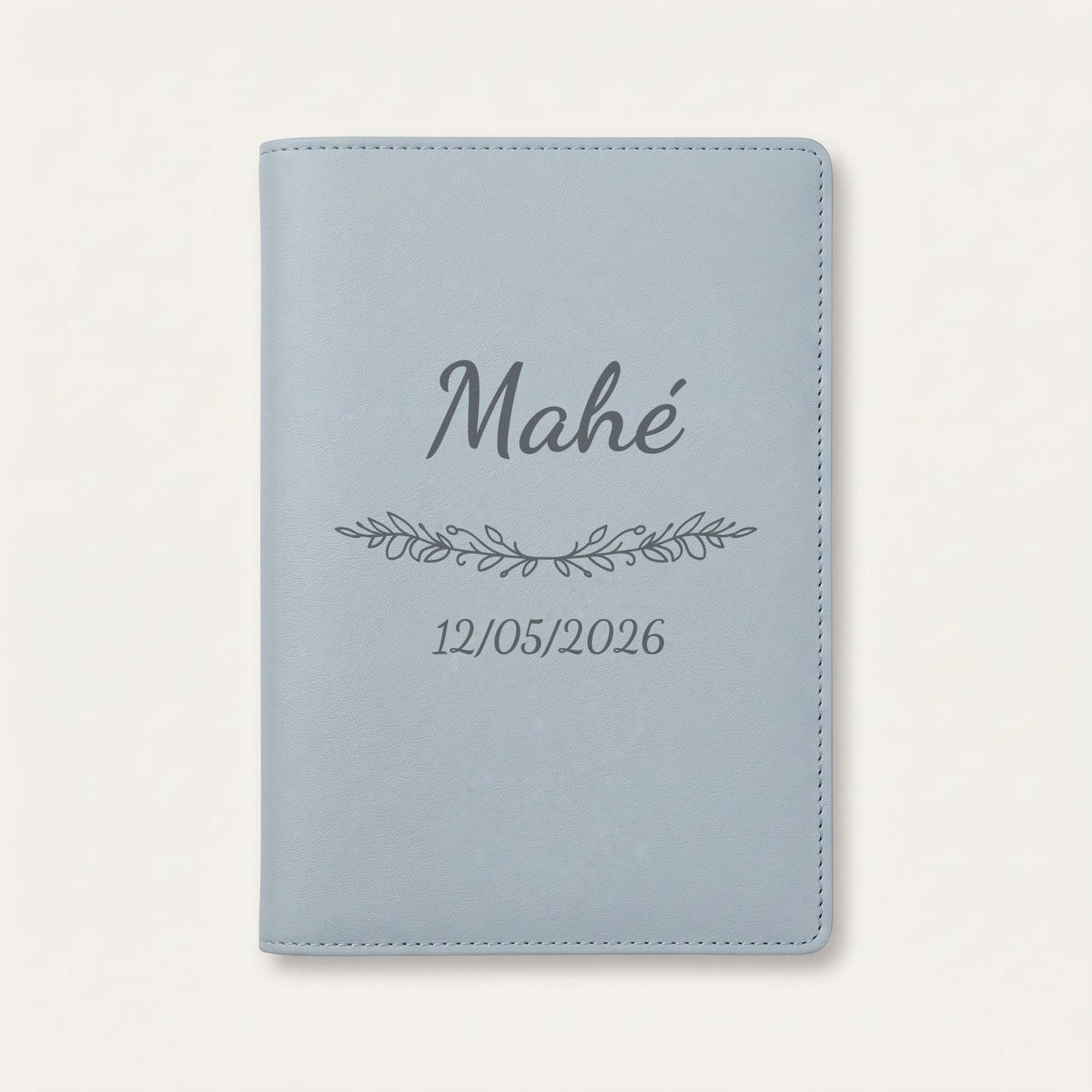 Protège carnet de santé personnalisé Mahé — Bleu nuage — prénom « Mahé », ornement Guirlande et date de naissance « 12/05/2026 » gravés