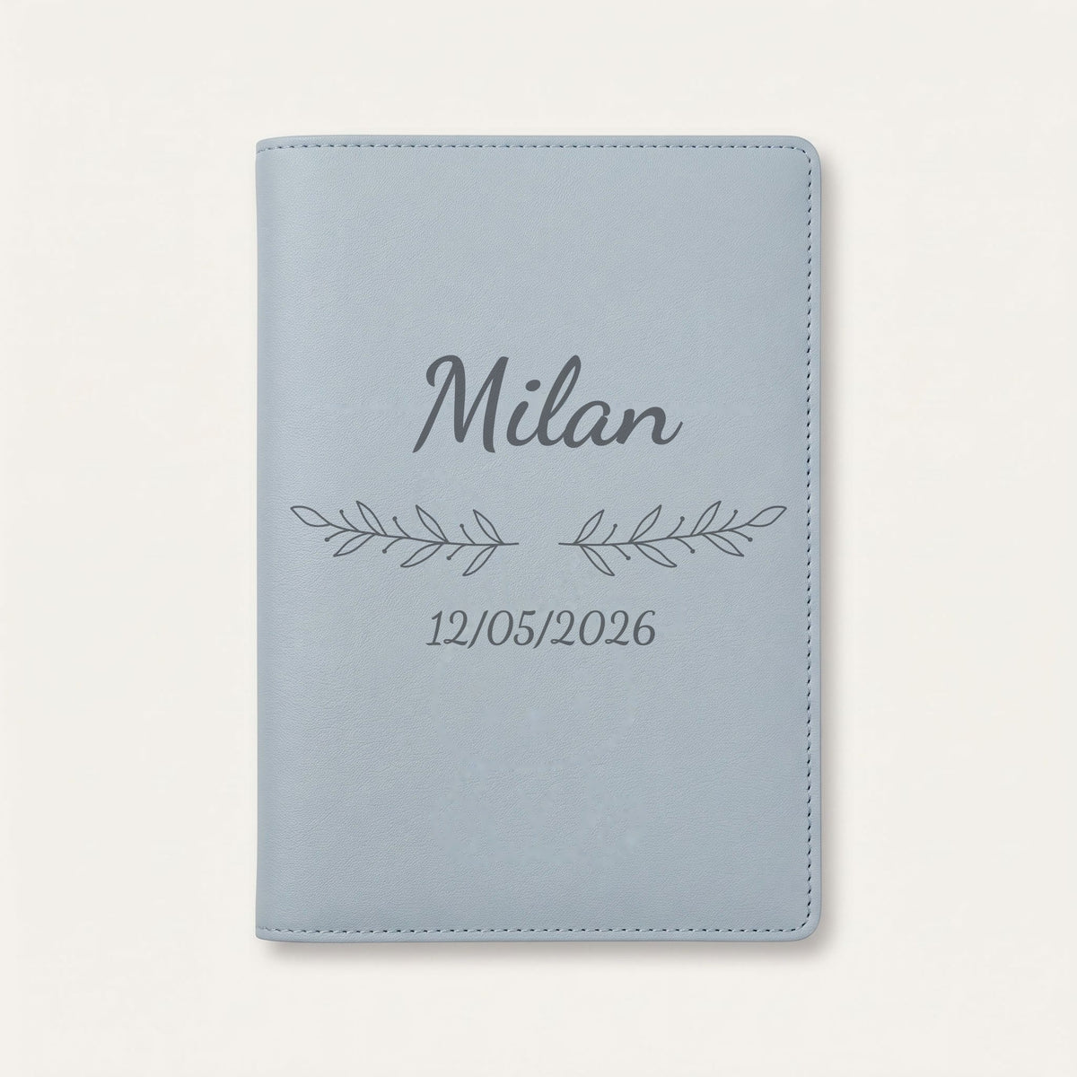 Protège carnet de santé personnalisé Milan — Bleu nuage — prénom « Milan », ornement Rameaux et date de naissance « 12/05/2026 » gravés