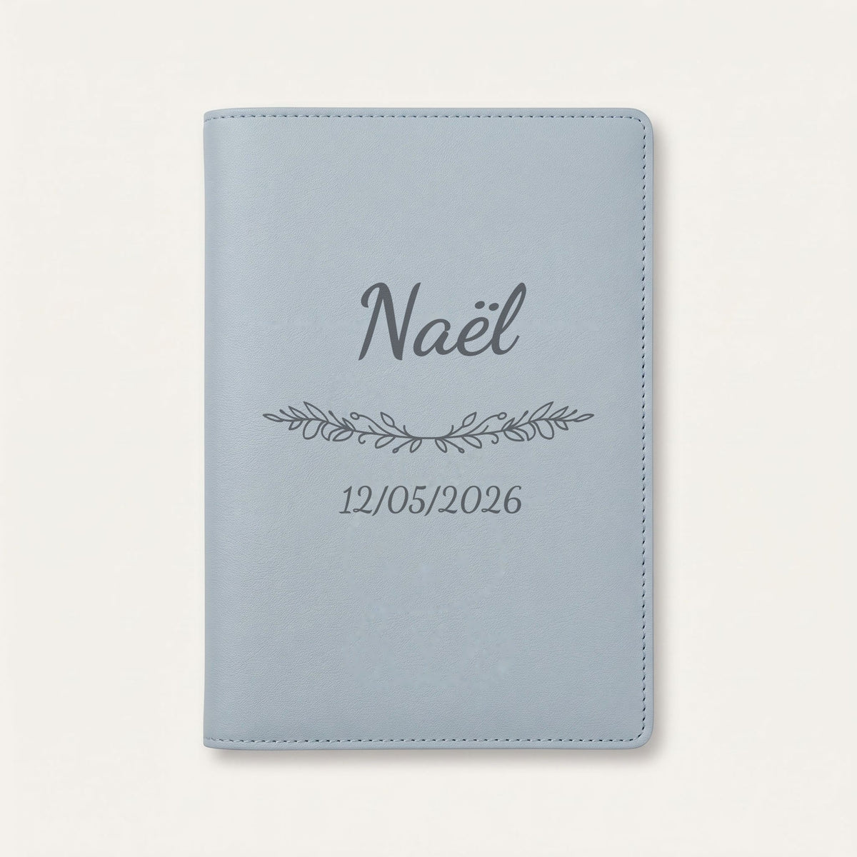 Protège carnet de santé personnalisé Naël — Bleu nuage — prénom « Naël », ornement Guirlande et date de naissance « 12/05/2026 » gravés