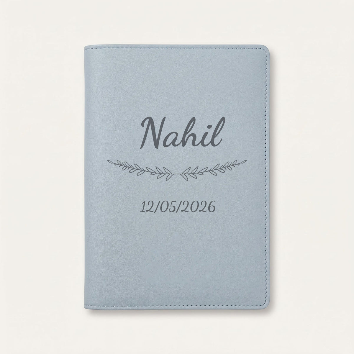 Protège carnet de santé personnalisé Nahil — Bleu nuage — prénom « Nahil », ornement Brindilles et date de naissance « 12/05/2026 » gravés
