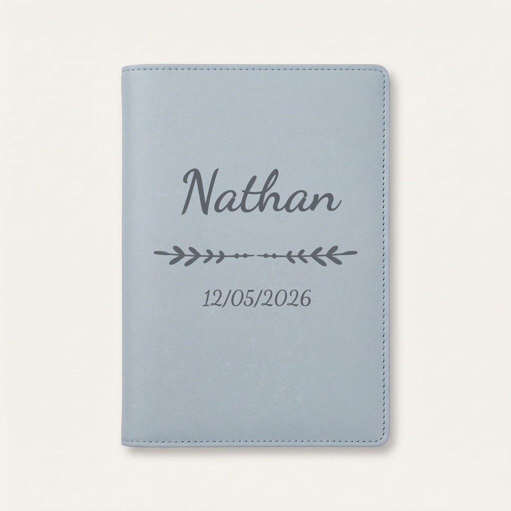 Protège carnet de santé personnalisé Nathan — Bleu nuage — prénom « Nathan », ornement Flèche et date de naissance « 12/05/2026 » gravés