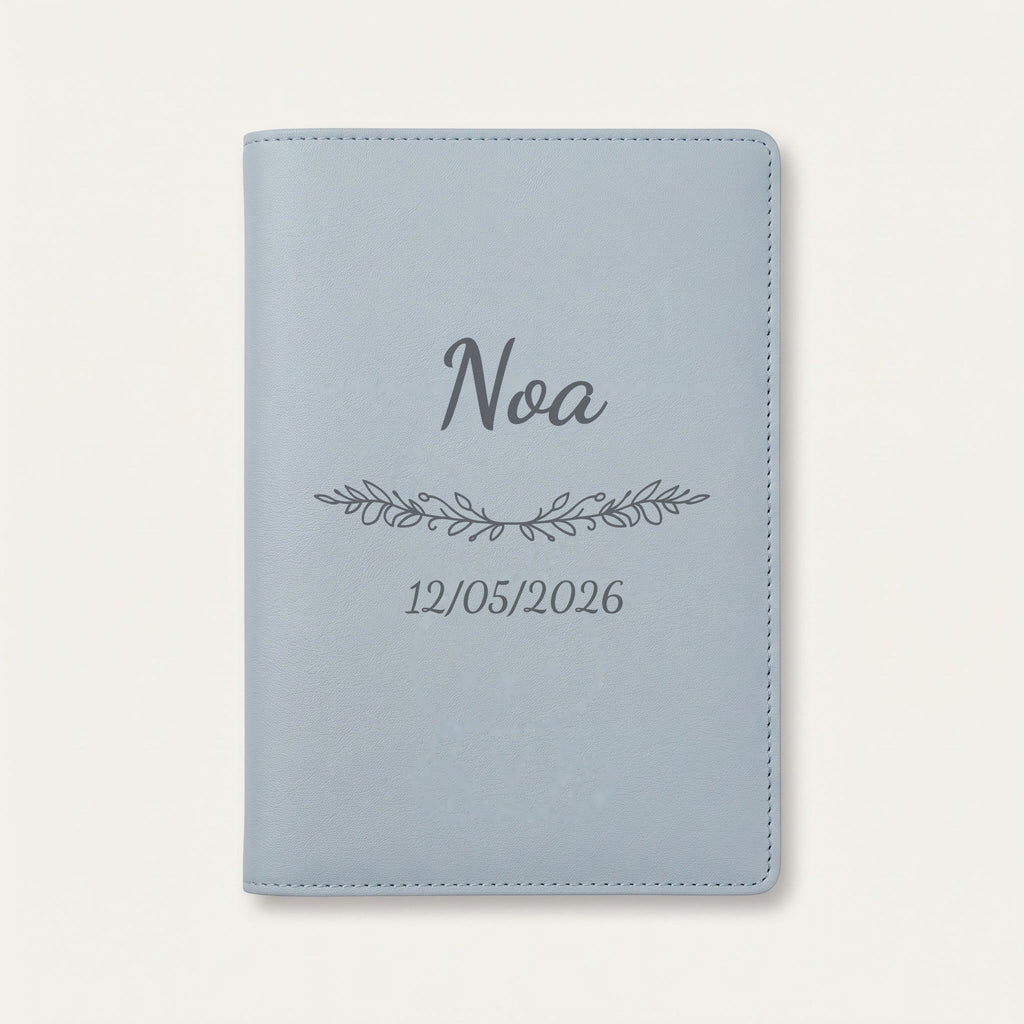 Protège carnet de santé personnalisé Noa — Bleu nuage — prénom « Noa », ornement Guirlande et date de naissance « 12/05/2026 » gravés