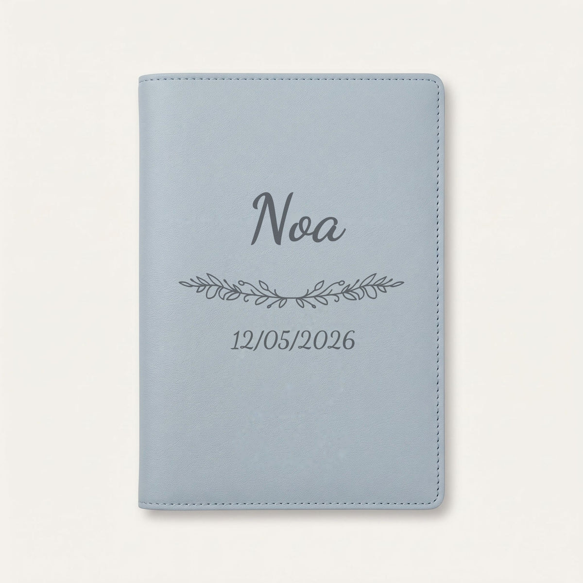 Protège carnet de santé personnalisé Noa — Bleu nuage — prénom « Noa », ornement Guirlande et date de naissance « 12/05/2026 » gravés