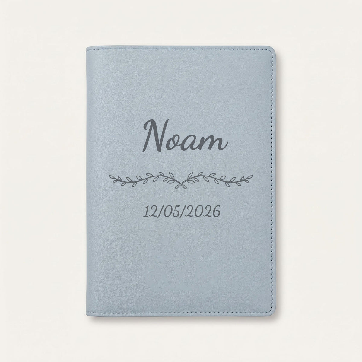 Protège carnet de santé personnalisé Noam — Bleu nuage — prénom « Noam », ornement Liane et date de naissance « 12/05/2026 » gravés