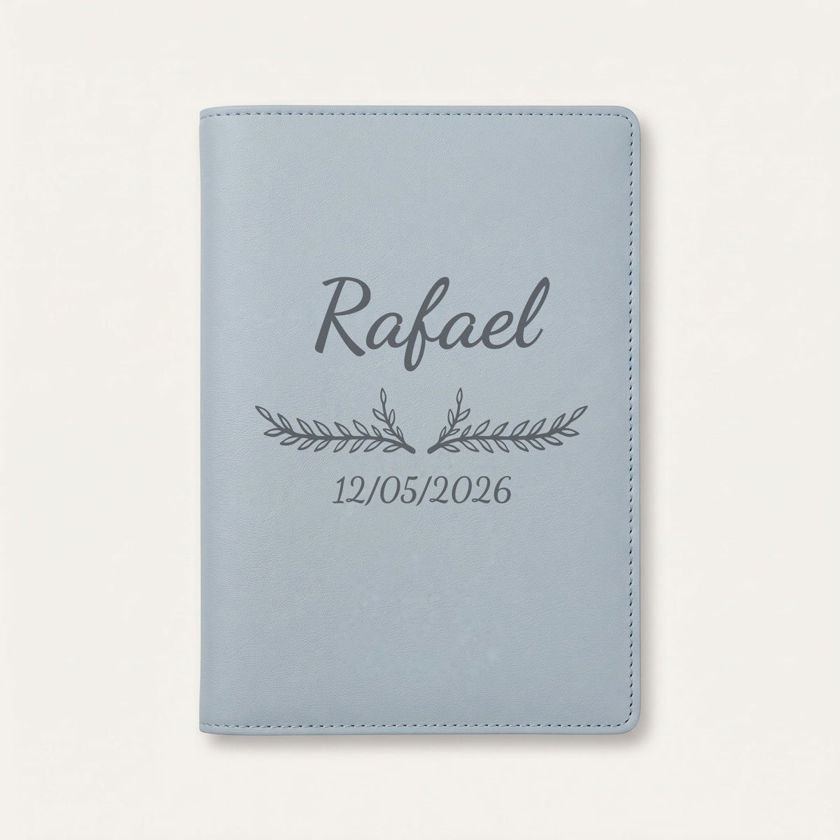 Protège carnet de santé personnalisé Rafael — Bleu nuage — prénom « Rafael », ornement Bouquet et date de naissance « 12/05/2026 » gravés