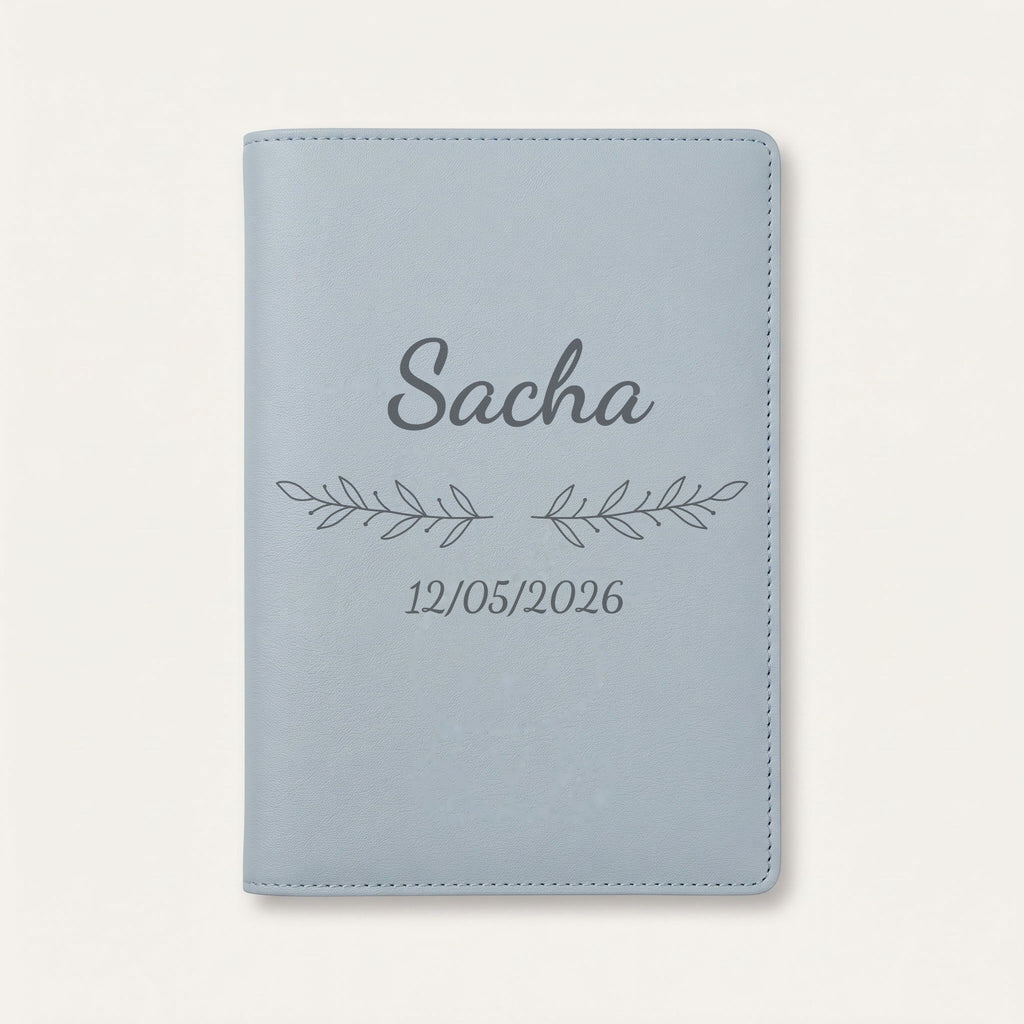 Protège carnet de santé personnalisé Sacha — Bleu nuage — prénom « Sacha », ornement Rameaux et date de naissance « 12/05/2026 » gravés