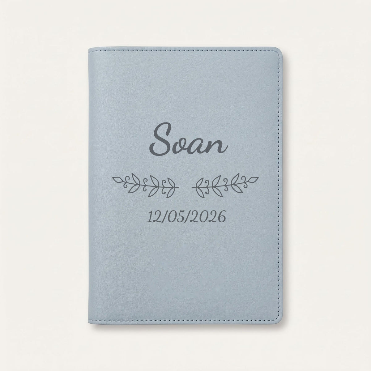 Protège carnet de santé personnalisé Soan — Bleu nuage — prénom « Soan », ornement Volutes et date de naissance « 12/05/2026 » gravés