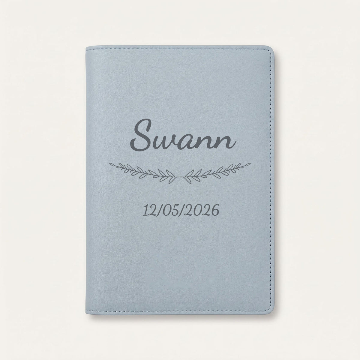 Protège carnet de santé personnalisé Swann — Bleu nuage — prénom « Swann », ornement Brindilles et date de naissance « 12/05/2026 » gravés