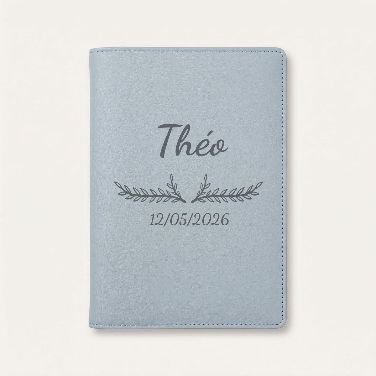 Protège carnet de santé personnalisé Théo — Bleu nuage — prénom « Théo », ornement Bouquet et date de naissance « 12/05/2026 » gravés