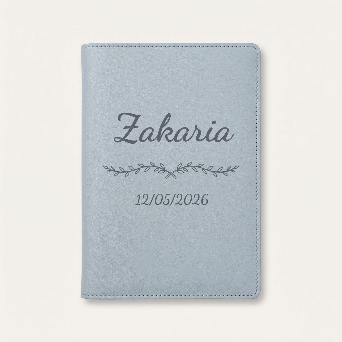 Protège carnet de santé personnalisé Zakaria — Bleu nuage — prénom « Zakaria », ornement Liane et date de naissance « 12/05/2026 » gravés
